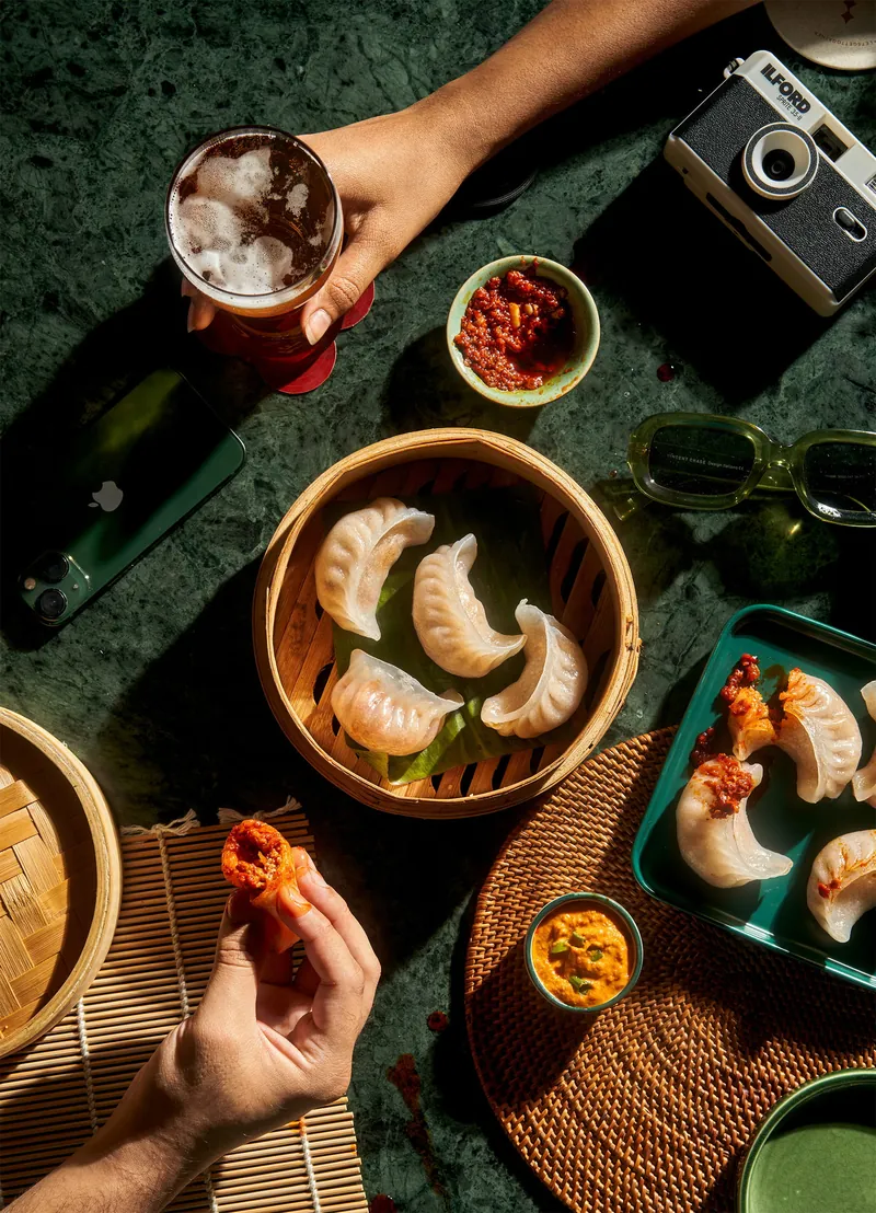 Dumplings, chili oil and drinks shared on a green marble table