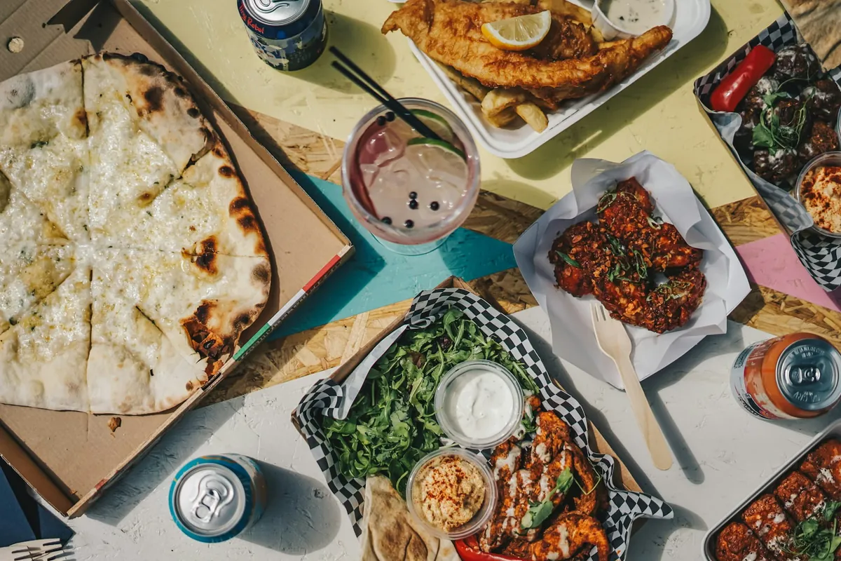 Pizza, wings, salad and drinks spread across a table