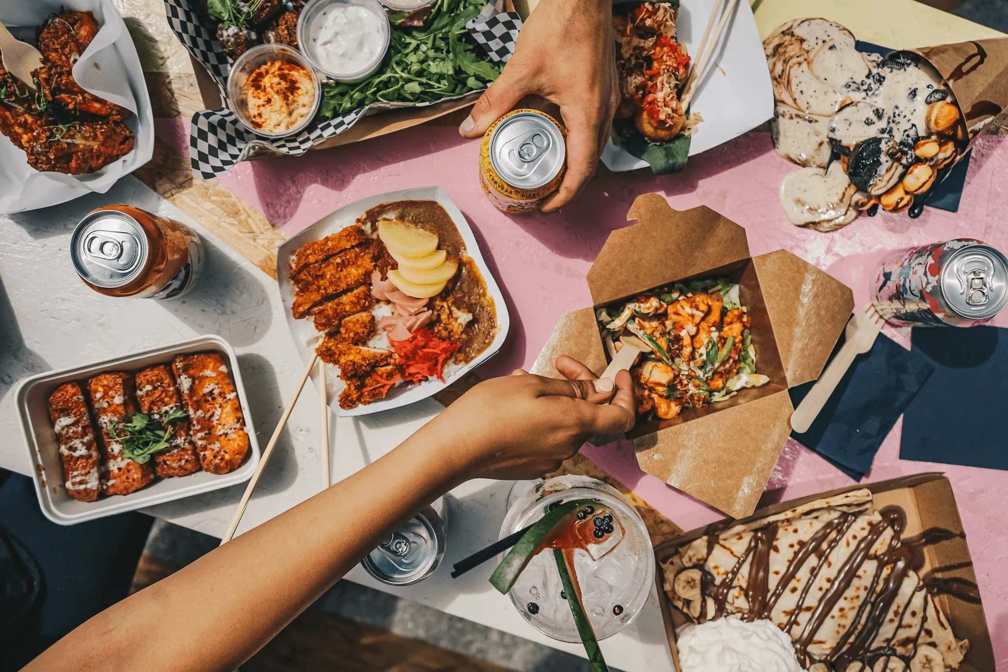 Friends sharing takeout around a pink table